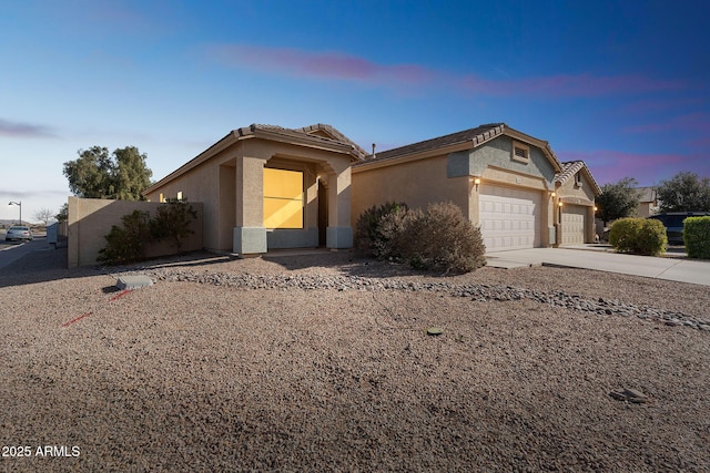 view of front facade featuring a garage, a tile roof, concrete driveway, and stucco siding