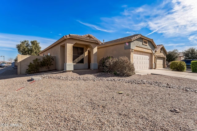 view of front of house with a garage, a tiled roof, concrete driveway, and stucco siding