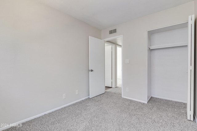 unfurnished bedroom featuring a closet and light carpet