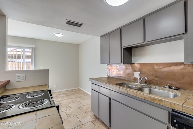 kitchen featuring appliances with stainless steel finishes, sink, tile countertops, gray cabinets, and decorative backsplash