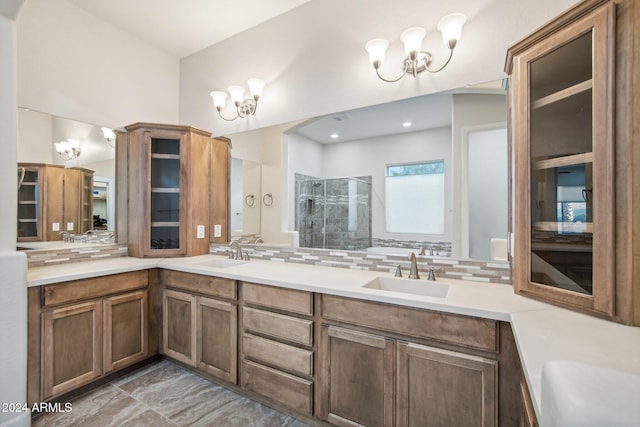 bathroom featuring tasteful backsplash, vanity, an enclosed shower, and a notable chandelier