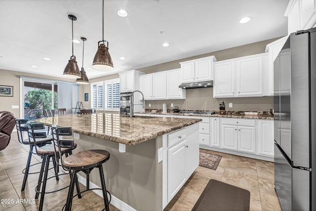 12932 W Cassia Trl, Peoria, AZ 85383 - kitchen with appliances with stainless steel finishes, under cabinet range hood, white cabinets, a large island, and recessed lighting