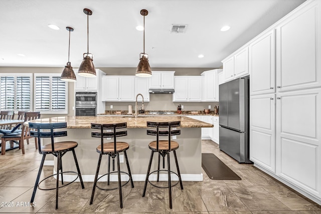 12932 W Cassia Trl, Peoria, AZ 85383 - kitchen featuring stainless steel appliances, recessed lighting, white cabinets, a kitchen bar, and a kitchen island with sink