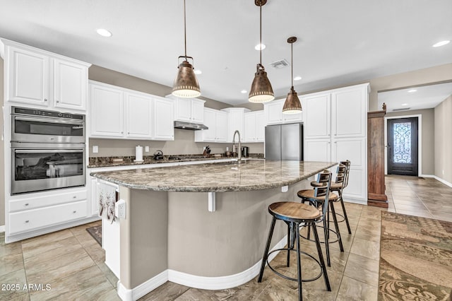 12932 W Cassia Trl, Peoria, AZ 85383 - kitchen featuring appliances with stainless steel finishes, white cabinetry, light stone counters, a large island, and recessed lighting