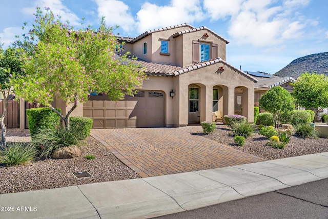 12932 W Cassia Trl, Peoria, AZ 85383 - mediterranean / spanish-style home featuring a tile roof, stucco siding, an attached garage, decorative driveway, and a mountain view