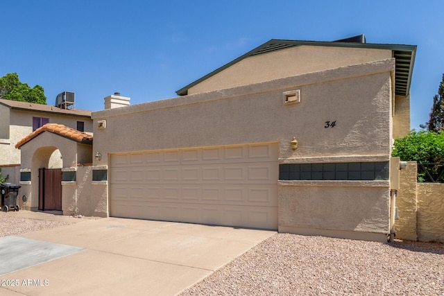 619 E Jensen St Unit 34, Mesa, AZ 85203 - view of front of home featuring stucco siding, an attached garage, a gate, driveway, and central AC