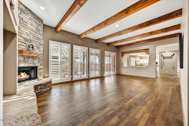 unfurnished living room with beam ceiling, a stone fireplace, and dark hardwood / wood-style flooring