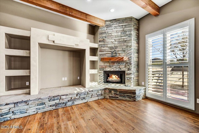 unfurnished living room with hardwood / wood-style flooring, a fireplace, built in features, and beamed ceiling