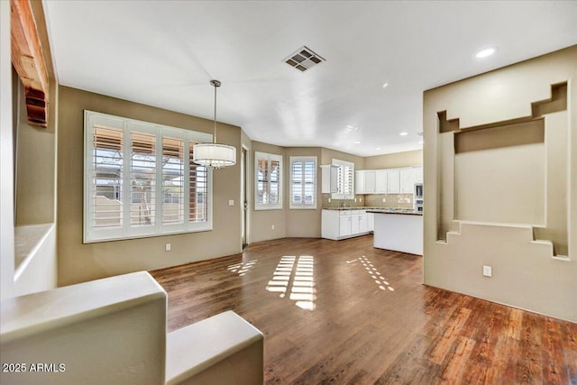 interior space featuring white cabinetry, hanging light fixtures, decorative backsplash, and dark hardwood / wood-style flooring