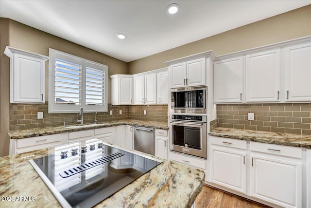 kitchen with sink, white cabinetry, tasteful backsplash, stainless steel appliances, and light stone countertops