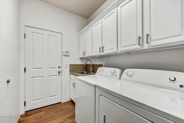 laundry room featuring cabinets, washing machine and clothes dryer, sink, and hardwood / wood-style floors