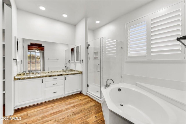 bathroom featuring wood-type flooring, plus walk in shower, and vanity