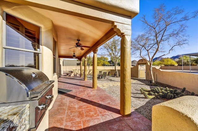 view of patio / terrace with a mountain view, an outdoor kitchen, ceiling fan, and grilling area