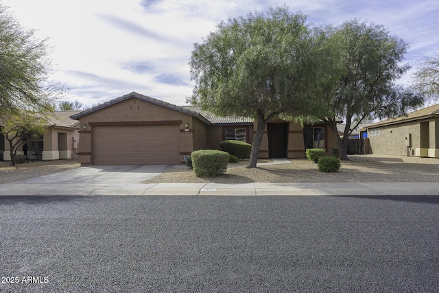 ranch-style home featuring driveway, an attached garage, a tile roof, and stucco siding