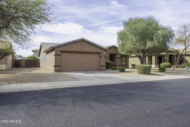 view of front facade with driveway, a tiled roof, an attached garage, fence, and stucco siding