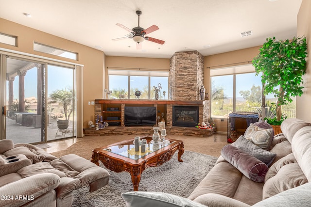 living room with light carpet, plenty of natural light, ceiling fan, and a stone fireplace