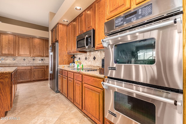 kitchen featuring appliances with stainless steel finishes, backsplash, light tile floors, and light stone counters