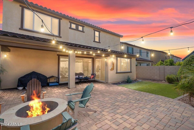 back house at dusk featuring an outdoor fire pit and a patio area