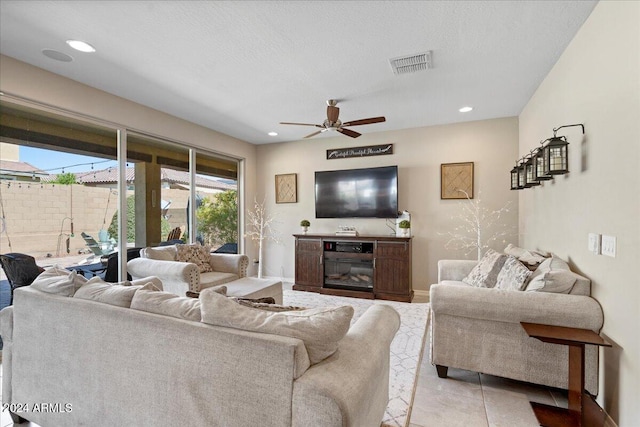 tiled living room with ceiling fan and a textured ceiling