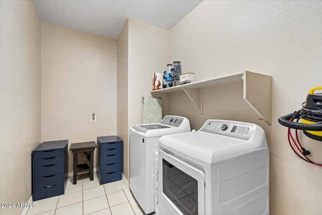 clothes washing area featuring light tile patterned flooring and washing machine and clothes dryer