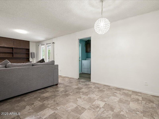 living area with washer / dryer, a textured ceiling, baseboards, and stone finish flooring