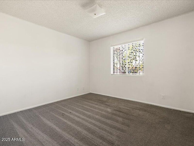 unfurnished room with a textured ceiling, dark colored carpet, and baseboards