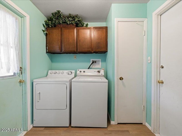 washroom featuring baseboards, light wood finished floors, independent washer and dryer, and cabinet space