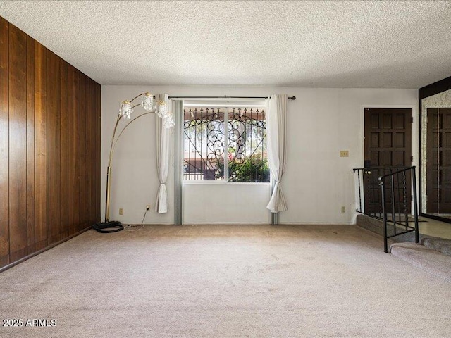 carpeted empty room with wood walls and a textured ceiling