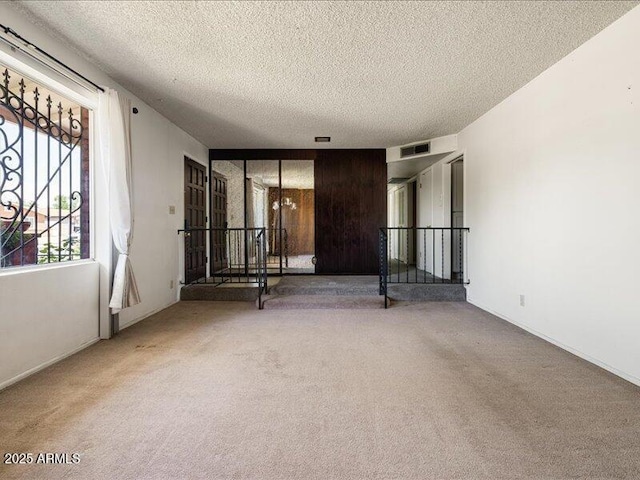spare room featuring carpet flooring, a textured ceiling, and visible vents