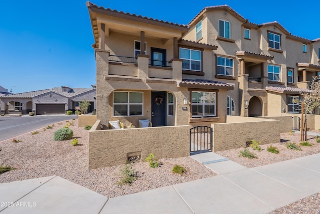 view of front facade featuring a fenced front yard, a gate, a residential view, and stucco siding