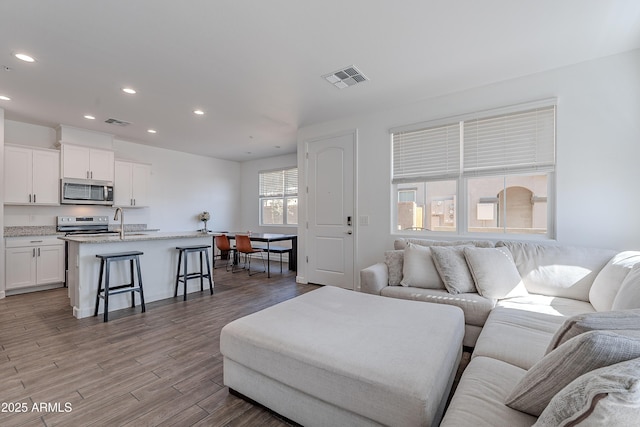 living room featuring recessed lighting, visible vents, and light wood finished floors