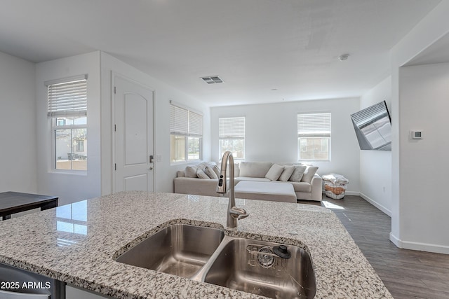 kitchen featuring dark wood-style floors, open floor plan, a sink, and light stone countertops