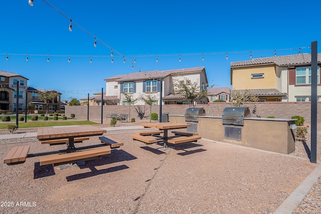 exterior space with a residential view, fence, a tiled roof, and an outdoor kitchen