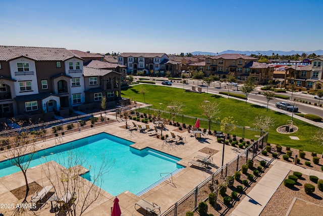 community pool with a mountain view, a patio, fence, and a residential view