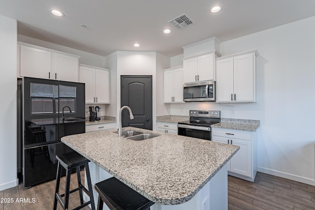 kitchen featuring appliances with stainless steel finishes, a sink, a center island with sink, and white cabinetry