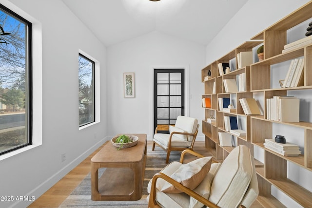 living area featuring lofted ceiling, wood finished floors, and baseboards