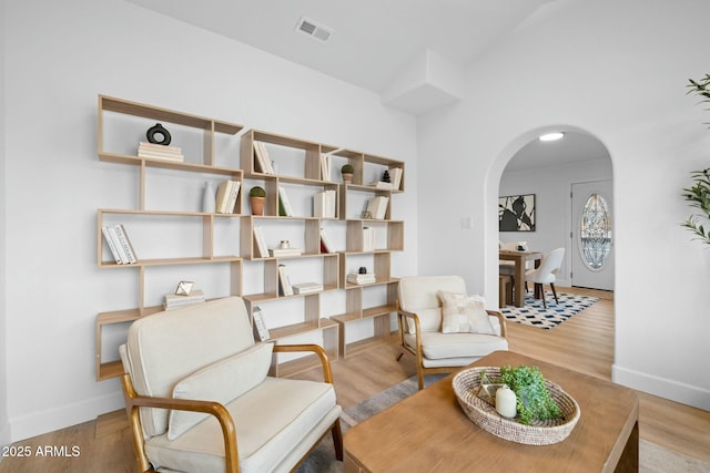 sitting room featuring arched walkways, visible vents, baseboards, and wood finished floors