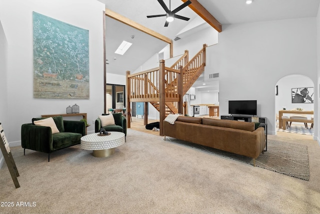 living room featuring visible vents, arched walkways, beamed ceiling, carpet, and stairs