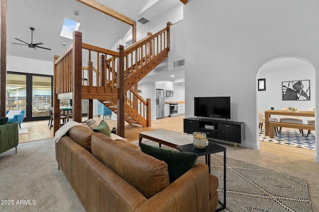 living room with arched walkways, stairway, visible vents, and a ceiling fan