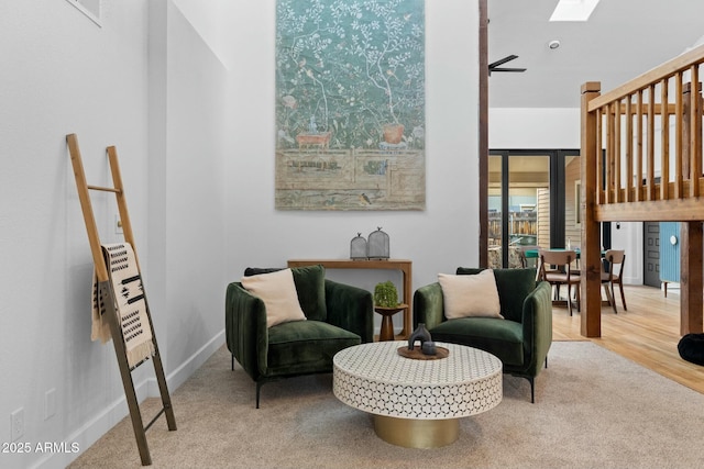 sitting room featuring carpet floors, a skylight, wood finished floors, and baseboards