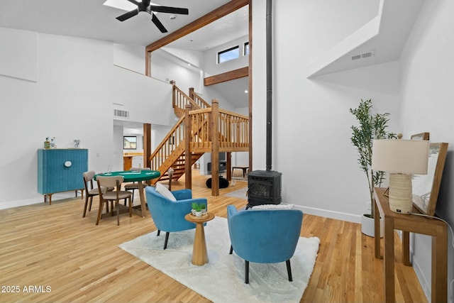 sitting room with high vaulted ceiling, visible vents, stairway, and wood finished floors