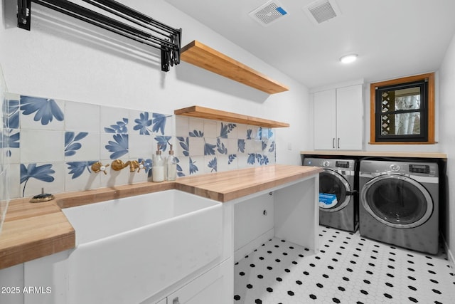 laundry area with a sink, independent washer and dryer, cabinet space, and visible vents