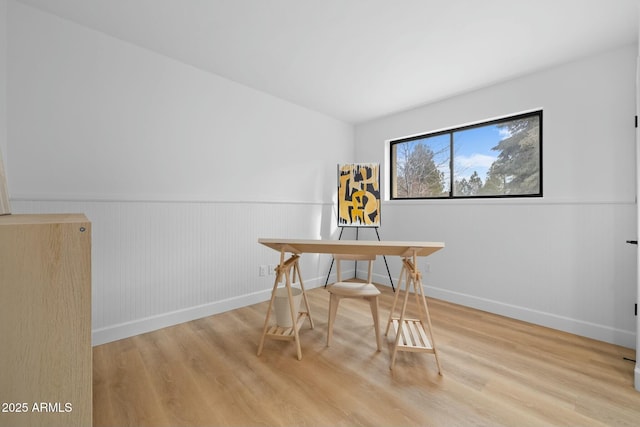 dining space with a wainscoted wall, wood finished floors, and baseboards