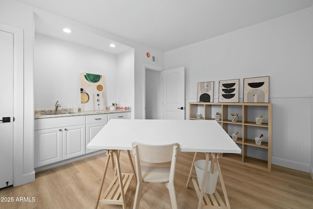 interior space featuring light wood finished floors, white cabinetry, a sink, and recessed lighting