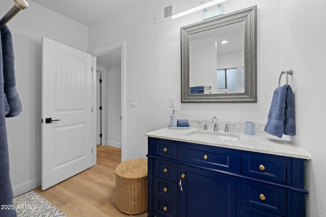 bathroom featuring visible vents, vanity, baseboards, and wood finished floors