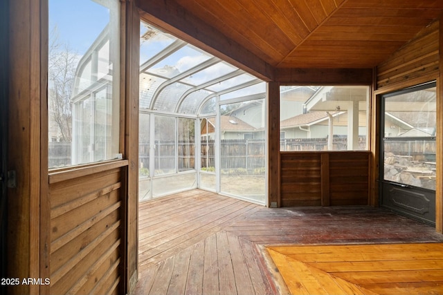 unfurnished sunroom featuring lofted ceiling, wooden ceiling, and a healthy amount of sunlight