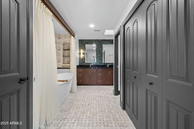 bathroom with a freestanding bath, double vanity, and a sink