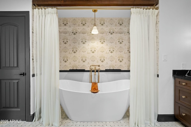 bathroom featuring wallpapered walls, a freestanding bath, and vanity