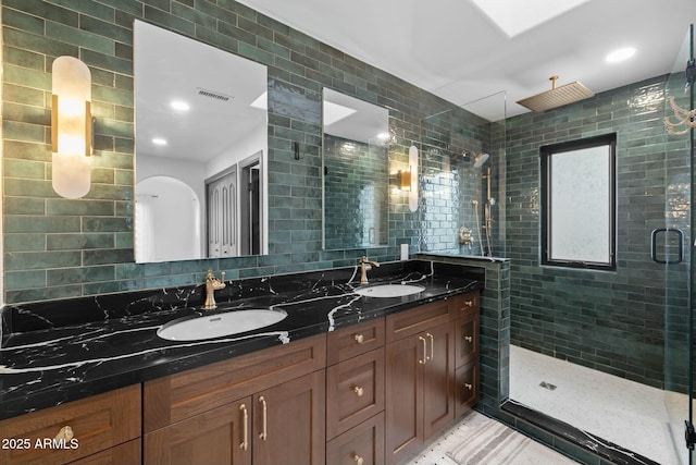 full bath with tile walls, visible vents, a sink, and a shower stall