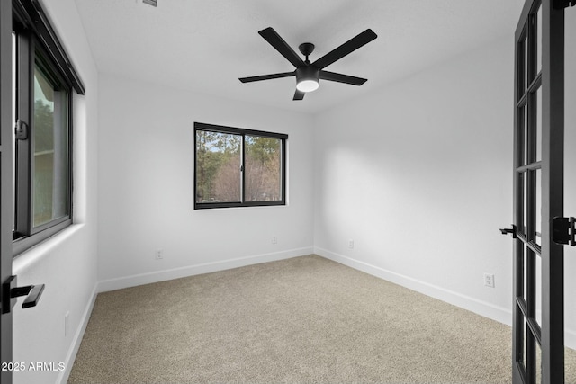 carpeted spare room featuring baseboards and a ceiling fan